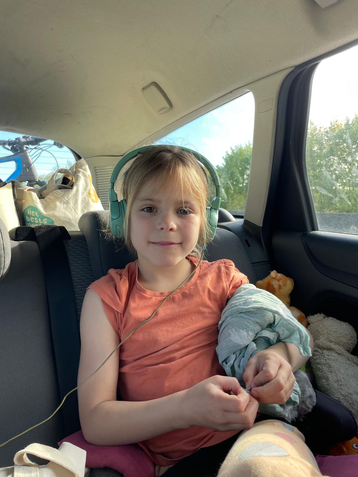 Girl in backseat of car listening with POGS